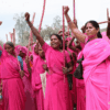 Women wearing pink traditional clothes and holding their fists up