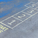 A hopscotch grid painted on pavement with the words ‘Start Here,’ symbolizing step-by-step processes like heuristic analysis.