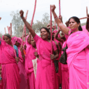 Women wearing pink traditional clothes and holding their fists up