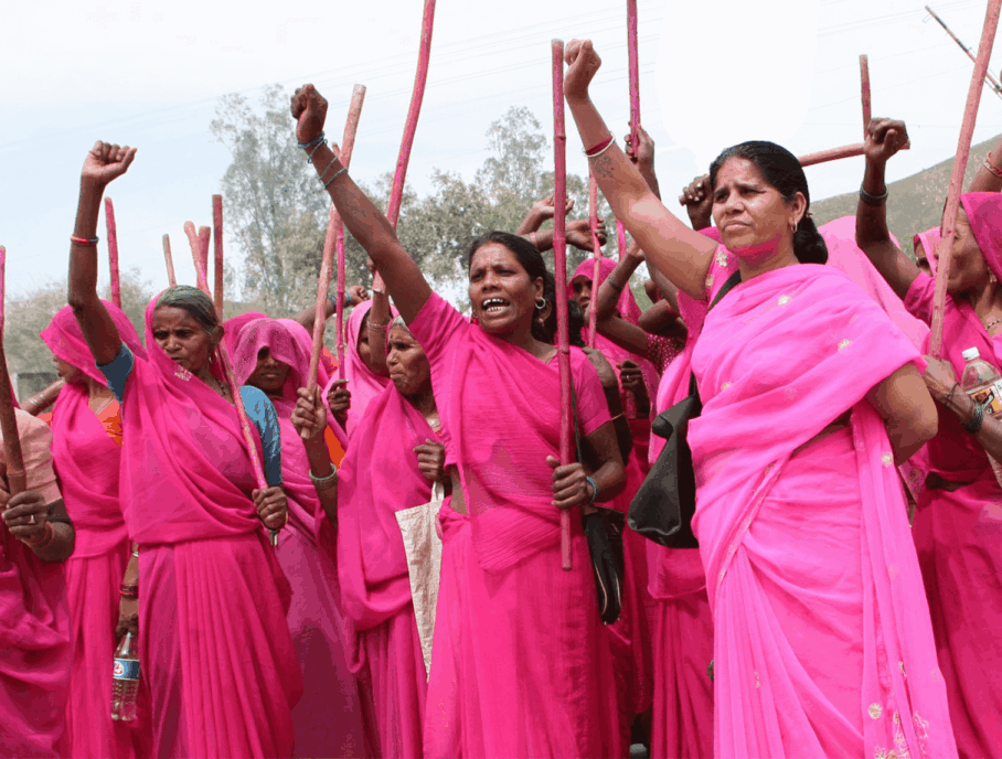 Women wearing pink traditional clothes and holding their fists up