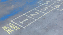 A hopscotch grid painted on pavement with the words ‘Start Here,’ symbolizing step-by-step processes like heuristic analysis.