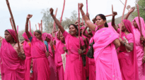 Women wearing pink traditional clothes and holding their fists up