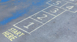 A hopscotch grid painted on pavement with the words ‘Start Here,’ symbolizing step-by-step processes like heuristic analysis.