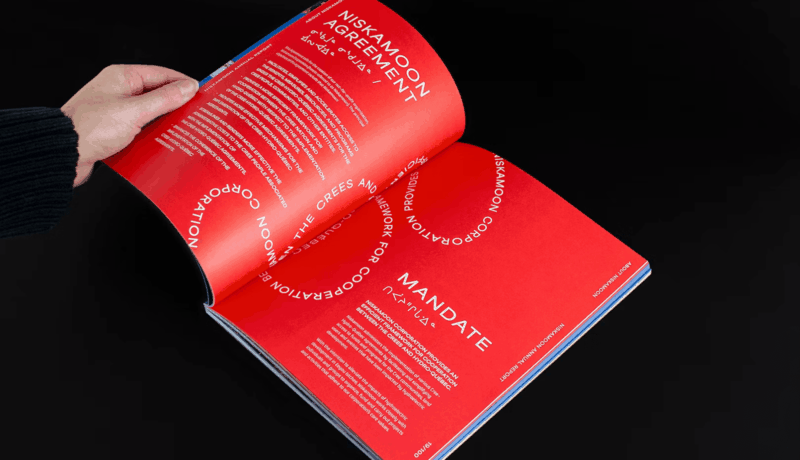 Hand opening the Niskamoon Corporation 2024–25 Report.